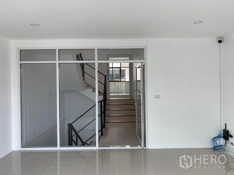 Home Office for rent in Wang Thonglang, Bangkok - Office area with glass partition overlooking staircase and window.