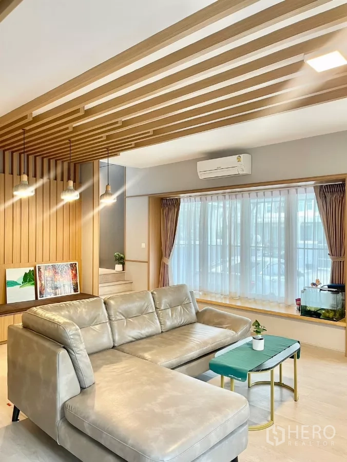 Detached House for rent in Prawet, Bangkok - Cozy lounge area with pendant lights, large curtained windows and sectional sofa.
