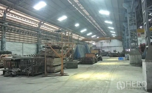 Factory for sale in Bang Phli, Samut Prakan - Long warehouse aisle with metal structure and bright roof lighting.