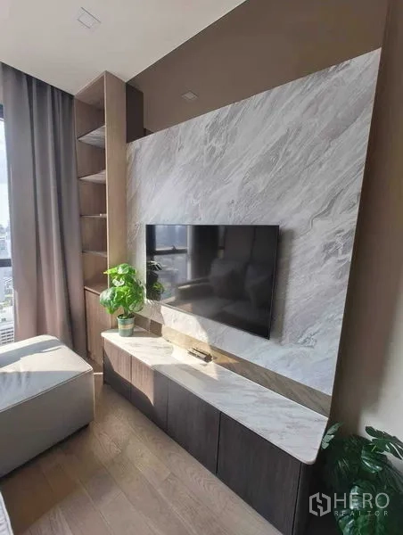 Condominium for rent in Watthana, Bangkok - Built-in TV wall with marble feature panel, floating cabinet, open shelves and an indoor plant by the window.