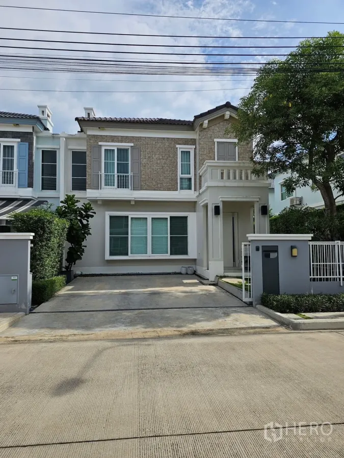 Detached House for rent in Prawet, Bangkok - Front facade of a detached house with driveway and balcony in Prawet’s Anya Bangna community.
