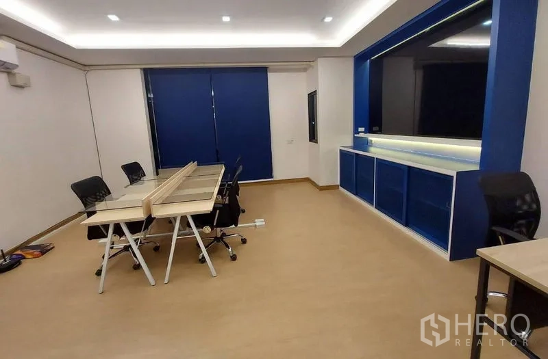 Townhouse for rent in Thanyaburi, Pathum Thani - Large multipurpose room set as an office with desks, blue built-in cabinet, and recessed ceiling lights.