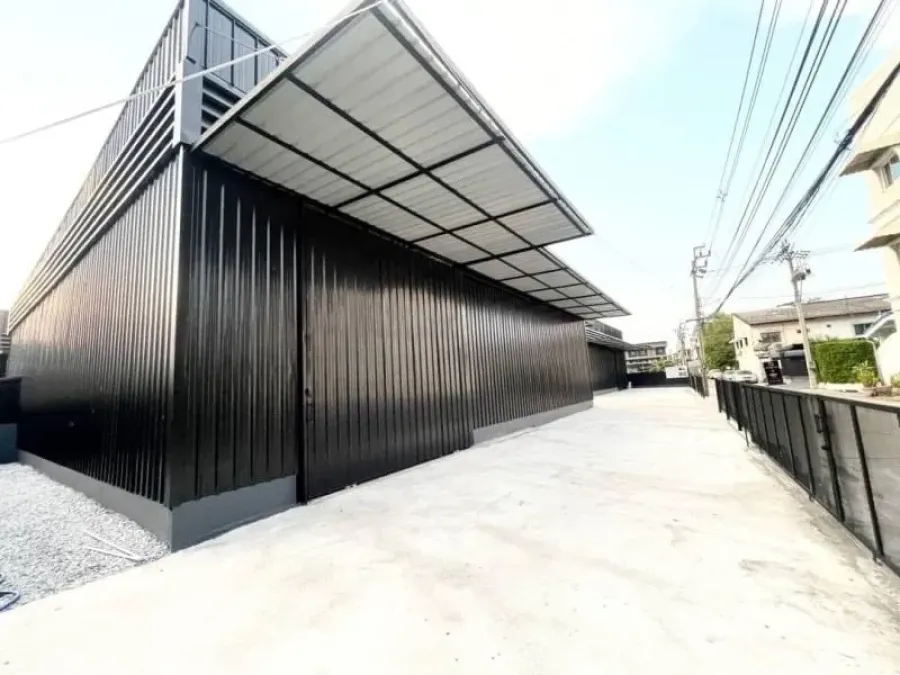 Warehouse for rent in Lat Phrao, Bangkok - Modern black metal warehouse exterior in Lat Phrao with covered loading canopy and a wide concrete driveway.