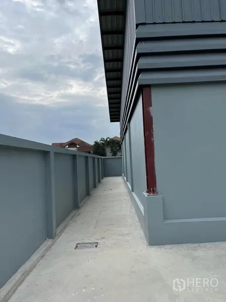 Warehouse for rent in Khlong Sam Wa, Bangkok - Side walkway along the warehouse with a high perimeter wall and drainage channel for easy maintenance.