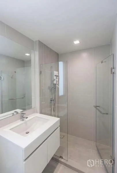 Detached House for rent or sale in Lat Phrao, Bangkok - Modern bathroom featuring a glass-enclosed shower, white vanity and light tiles.