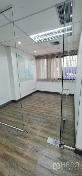 Office Space for rent in Watthana, Bangkok - Compact glass‑walled meeting room with wood‑look flooring and blinds.