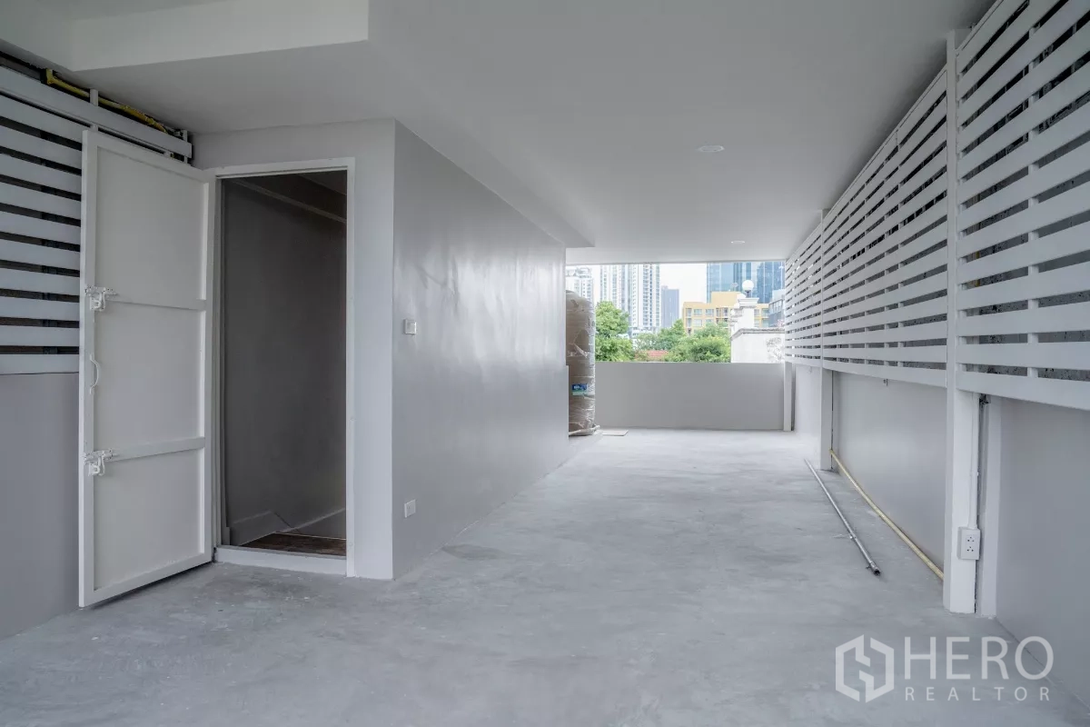 Townhouse for sale in Watthana, Bangkok - Covered upper terrace or utility area with storage room and partial city skyline views.
