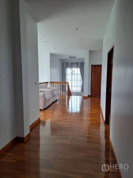 Detached House for rent in Prawet, Bangkok - Upper hallway with polished wood floors leading to a sitting area and balcony-style window.