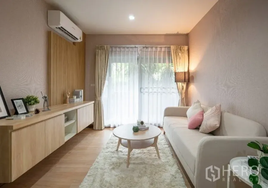 Condominium for sale - Cozy living room with shag rug, round coffee table and soft light from balcony curtains.