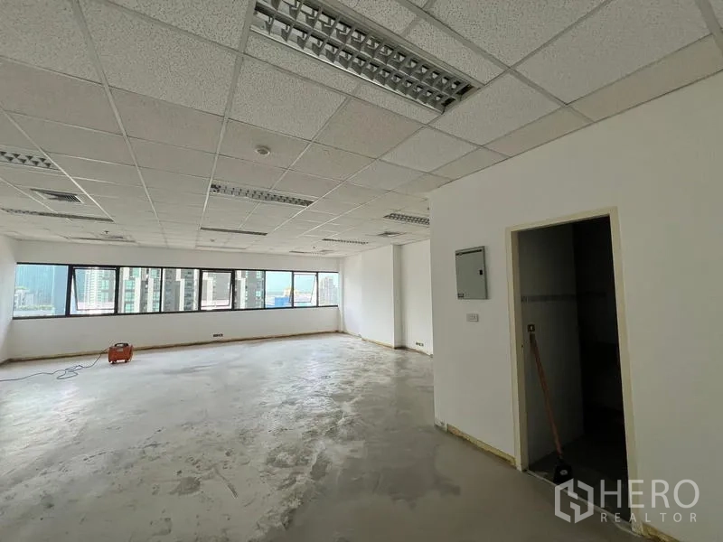 Office Space for rent in Watthana, Bangkok - Unfurnished bright office floor with ribbon windows, doorway to pantry or storage, and AC vents.