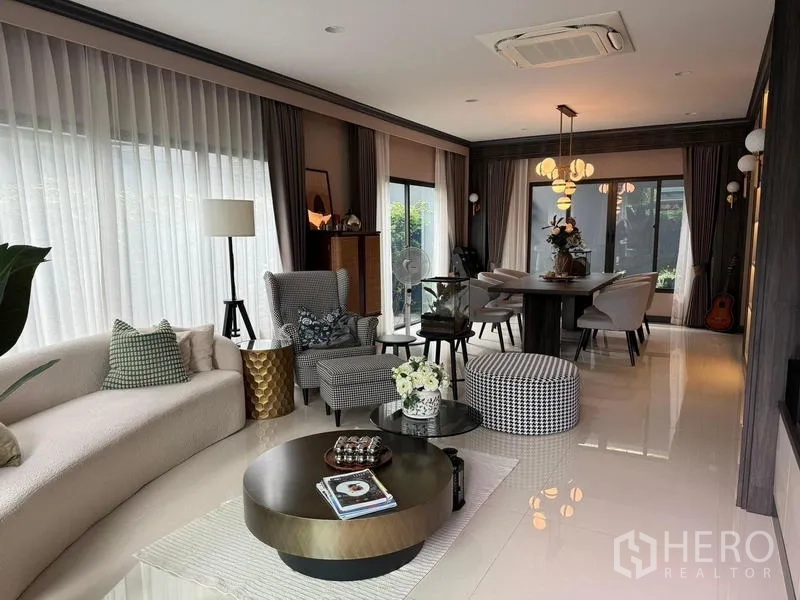 Detached House for rent in Bang Kapi, Bangkok - Bright living room flowing to dining area with full‑height windows and stylish furnishings.