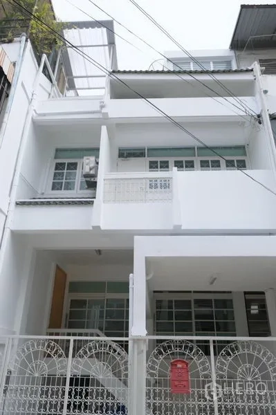 ทาวน์เฮาส์ ให้เช่าในKhlong Toei, Bangkok - ทาวน์เฮ้าส์ 3 ชั้นสีขาวพร้อมประตูรั้วและที่จอดรถหน้าอาคารในซอยเงียบสงบ