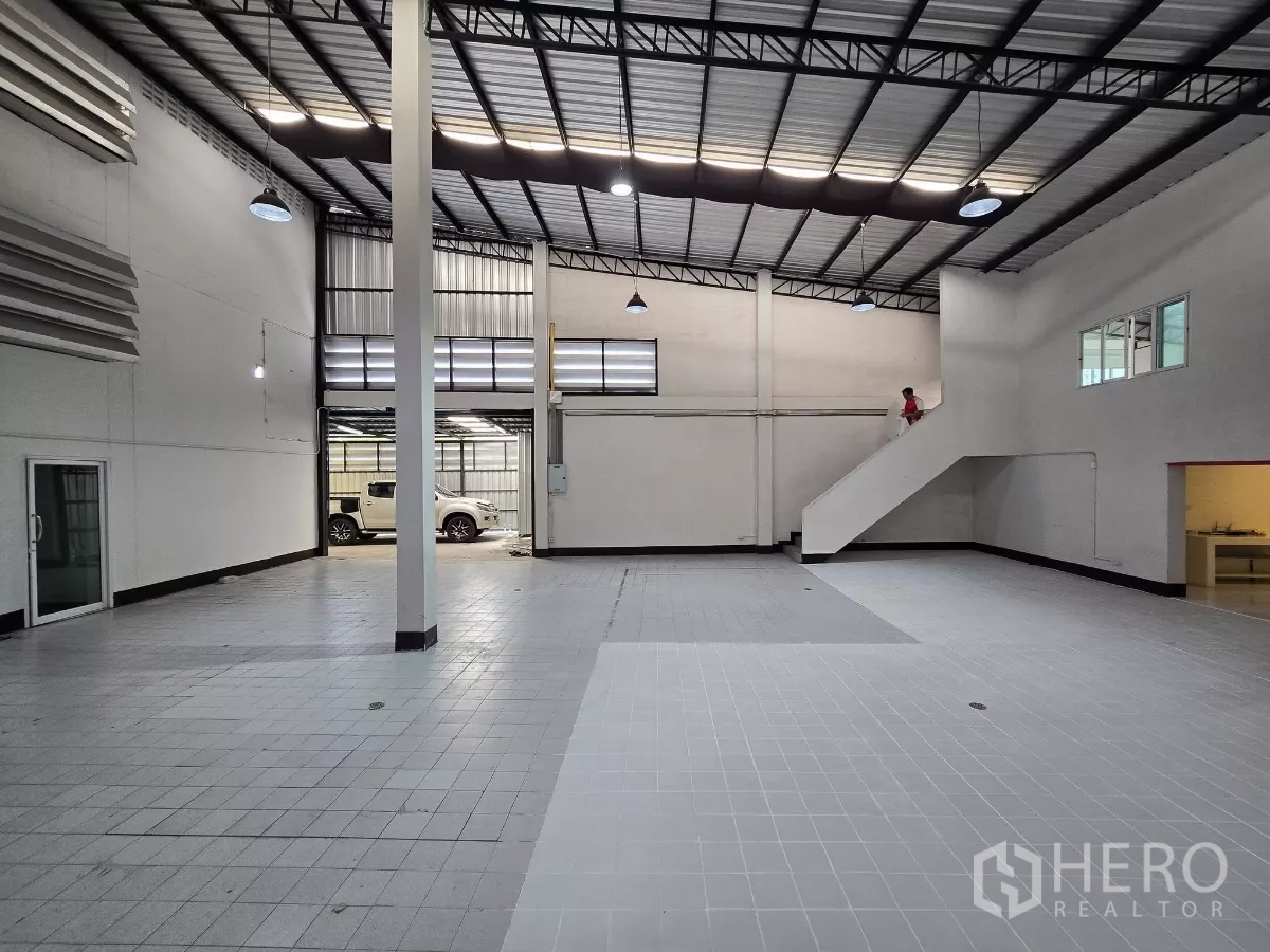 Warehouse for rent in Chatuchak, Bangkok - Open warehouse hall with skylights, tiled flooring and side staircase.