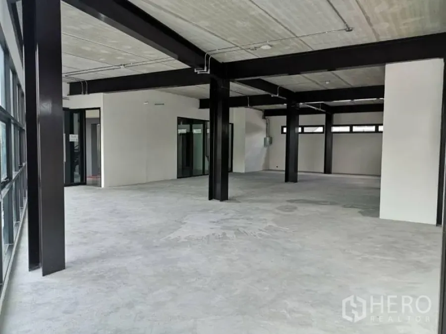 Office Space for rent in Chatuchak, Bangkok - Open-plan shell office with exposed ceiling, black steel beams, concrete flooring and large glass walls.