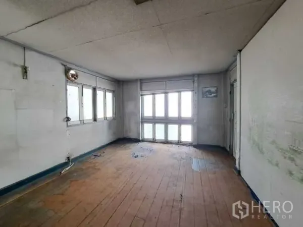 Retail Space for rent in Sathon, Bangkok - Corner room with multiple windows and aged wooden flooring ready for renovation.