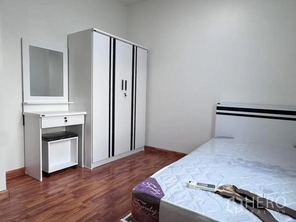 Townhouse for rent in Phra Khanong, Bangkok - Bedroom with wardrobe, dressing table, and bed on wood flooring.