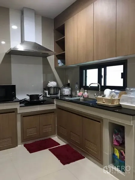 Detached House for rent in Bang Kapi, Bangkok - U-shaped modern kitchen with wood cabinetry, range hood and a window for ventilation.