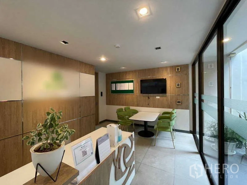 Home Office for rent in Watthana, Bangkok - Lobby nook with built-in cabinets, TV and round table seating.