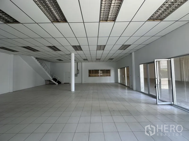 Factory for rent in Khlong Luang, Pathum Thani - Ground-floor office area with tiled flooring, grid ceiling, and glass partitions.