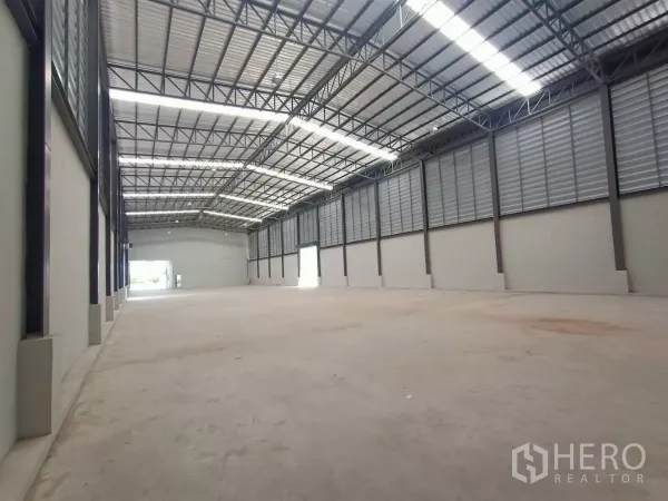 工厂 出租或出售在Mueang Samut Sakhon, Samut Sakhon - 仓库内部挑高空间，钢结构屋架，采光带与侧向通风百叶。