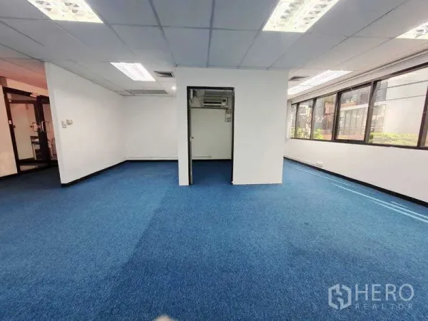 Office Space for rent in Khlong Toei, Bangkok - Spacious 72 sqm office showing blue carpet, white walls, and long side windows for daylight.