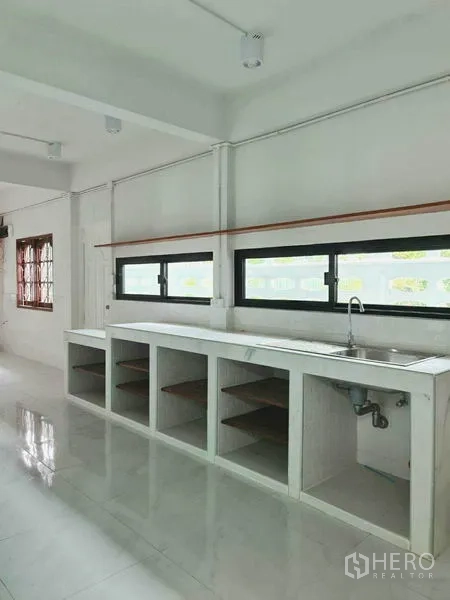 Home Office for rent in Lat Phrao, Bangkok - Long pantry with built-in sink and open cabinetry beneath horizontal windows.