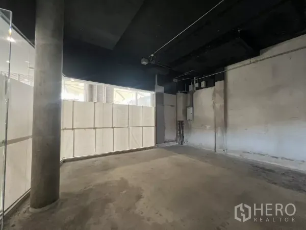 Retail Space for rent - Raw retail interior showing open-plan shell, concrete floor, black exposed ceiling and service points.