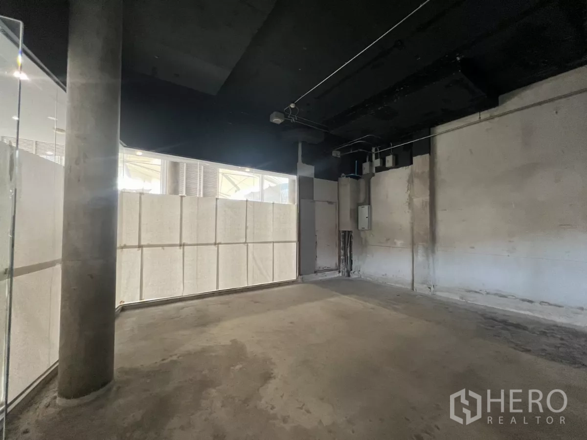 Retail Space for rent - Raw retail interior showing open-plan shell, concrete floor, black exposed ceiling and service points.