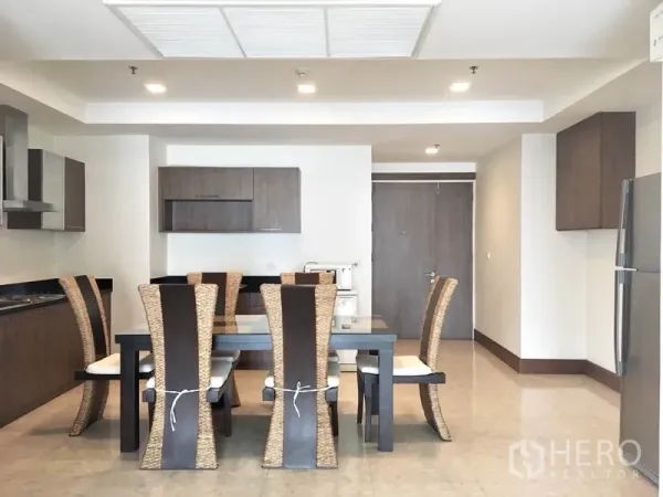 Condominium for rent in Khlong Toei, Bangkok - Open-plan kitchen and dining area with six-seat table and modern cabinetry.