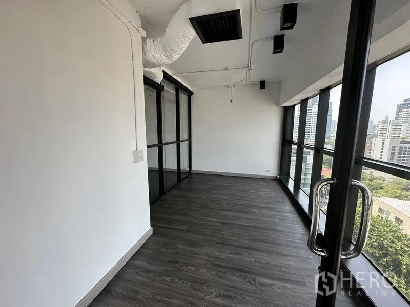 Office Space for rent - Long breakout or meeting area with full-height windows and dark flooring.