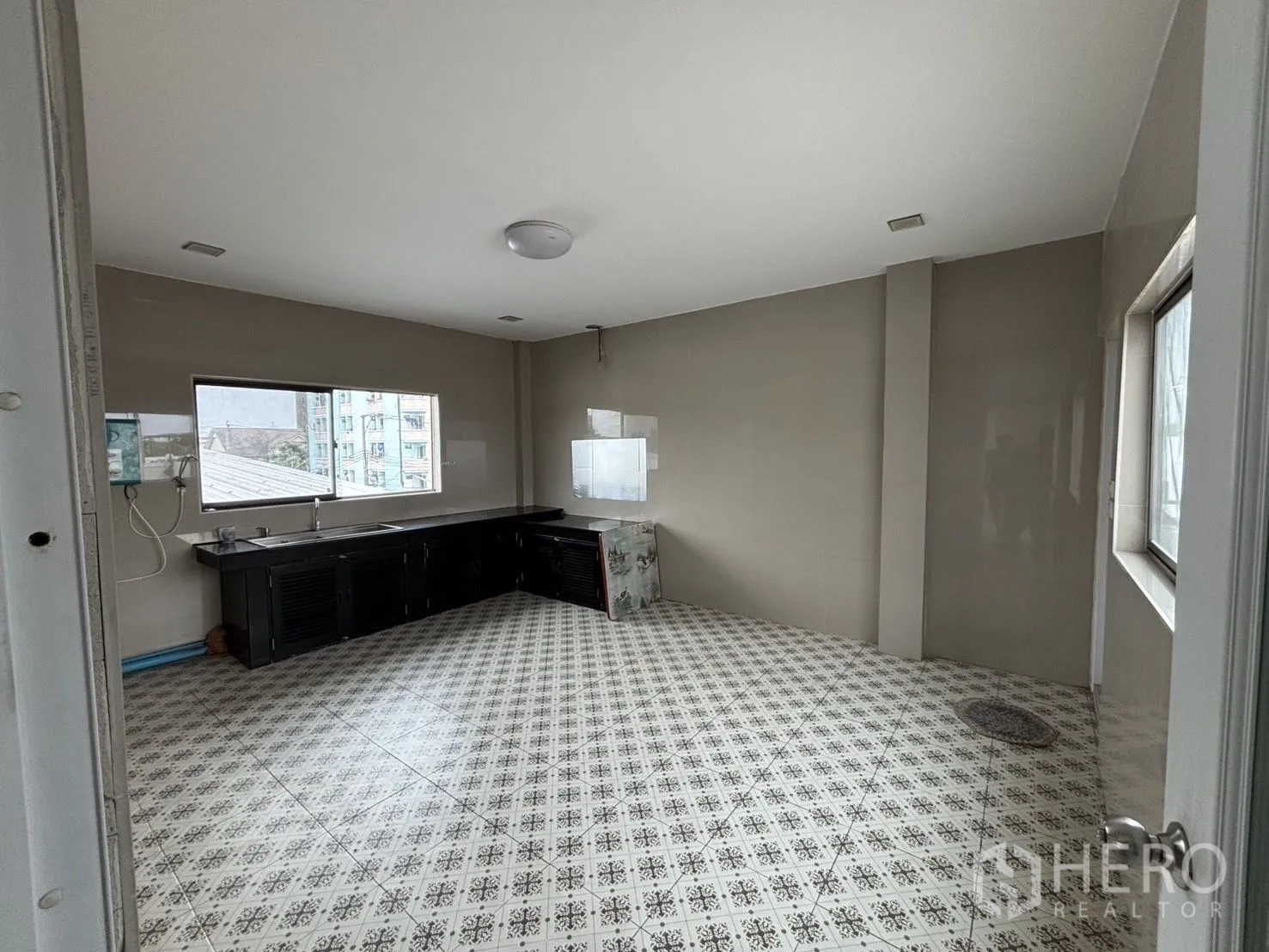 Warehouse for rent or sale in Wang Thonglang, Bangkok - Spacious kitchen with long counter, sink and patterned floor tiles.