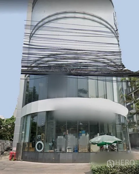 Retail Space for rent in Watthana, Bangkok - Corner retail building with curved double-height glass frontage and street-facing windows in Watthana, Bangkok.