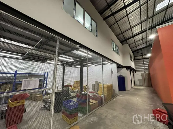 Warehouse for rent - Ground-floor caged storage and work area beside a two-storey office block with windows.