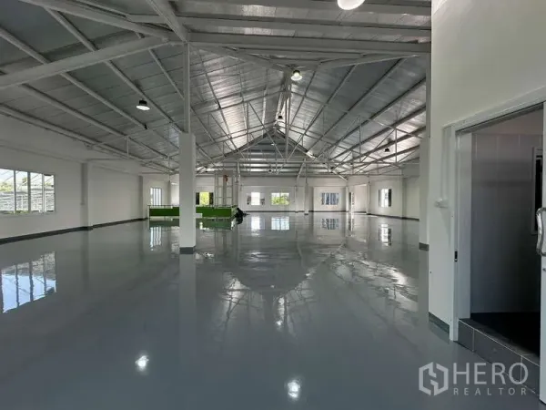 Warehouse for rent in Mueang Samut Prakan, Samut Prakan - Spacious production area under a metal roof with open layout and a side entry door.