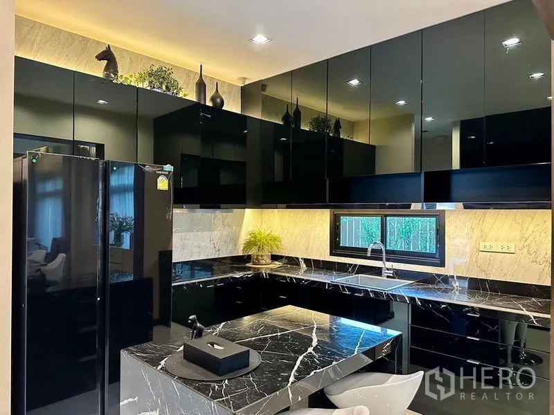 Detached House for rent - Modern black-and-marble kitchen with glossy cabinets, island and a window in a Bang Phli detached house.