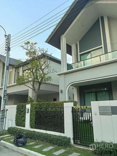 Detached House for rent in Bang Phli, Samut Prakan - Modern detached house exterior with gated front yard, balcony and driveway.