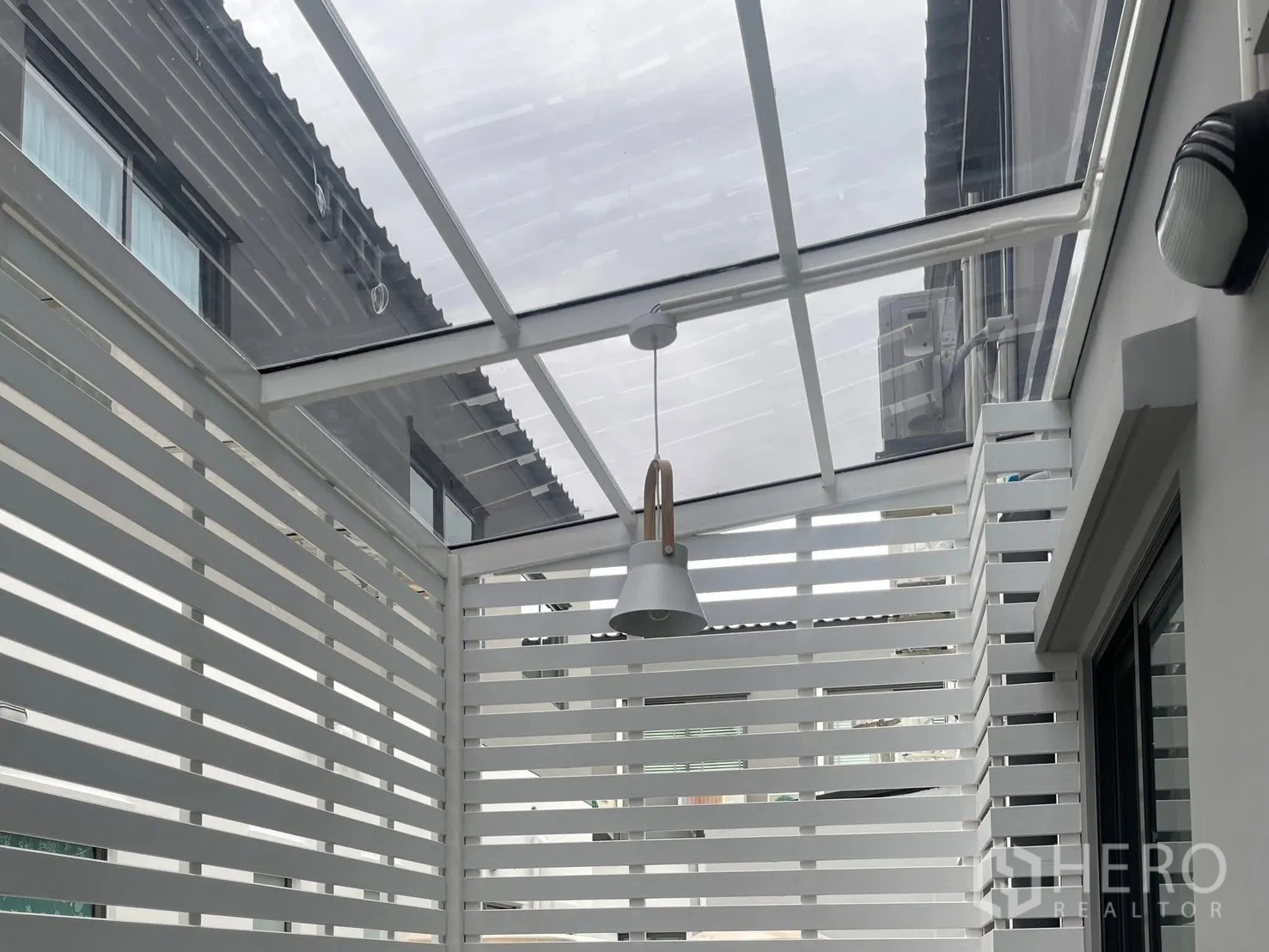 Townhouse for rent in Bang Phli, Samut Prakan - Private covered patio with white slatted privacy screens, clear roof panels, and a pendant light.