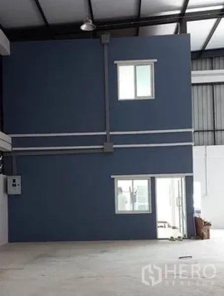 Warehouse for rent in Lam Luk Ka, Pathum Thani - Two-storey internal office unit with windows set inside the warehouse space.
