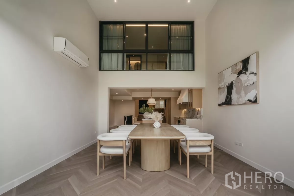 Townhouse for rent in Watthana, Bangkok - Formal dining room with tall ceiling and glass wall above.