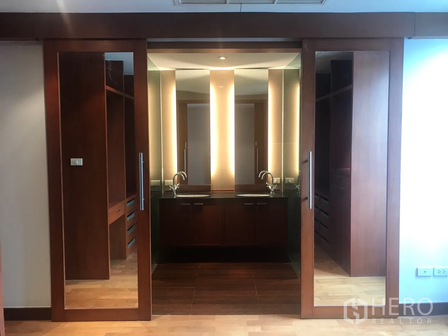 Home Office for rent in Watthana, Bangkok - Dressing area with mirrored sliding doors and double sinks set in warm wood cabinetry.