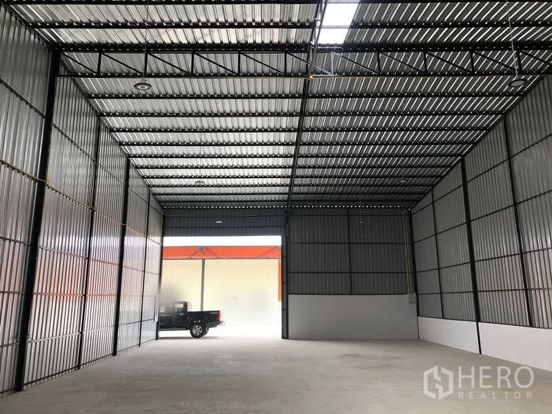 Warehouse for rent in Pathum Thani - Open-plan warehouse facing a large sliding door with a pickup truck at the loading bay.