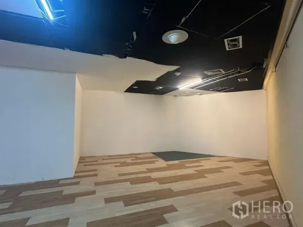 Retail Space for rent - Corner area of the retail space with white walls, recessed lighting and ventilation panels.