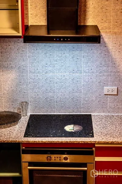 Townhouse for rent in Khlong Toei, Bangkok - Kitchen close-up showing granite countertop, cooktop, oven and range hood.
