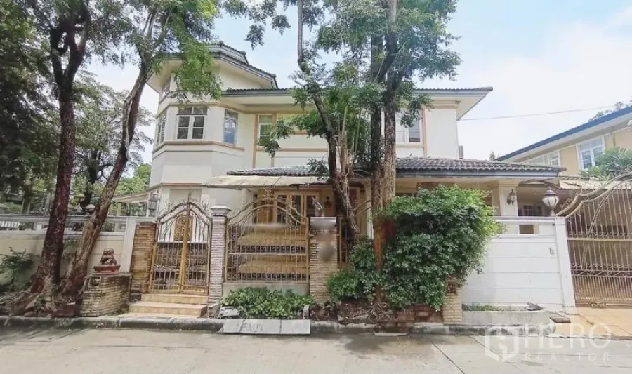 Detached House for sale in Bang Kapi, Bangkok - Two-storey detached house exterior with gated entrance, trees and perimeter wall.