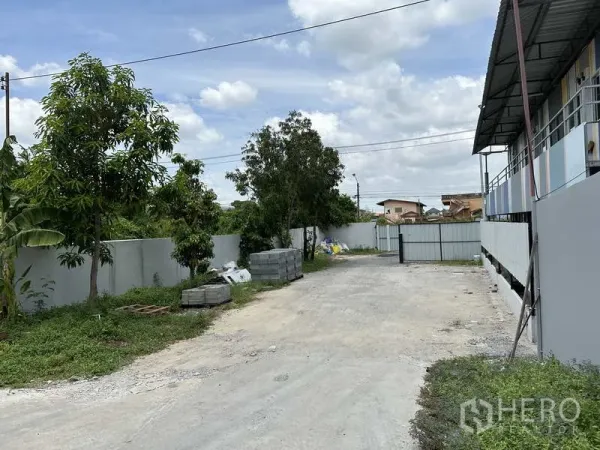 Warehouse for rent in Lat Krabang, Bangkok - Gated access road with boundary walls, trees and open yard space around the industrial site.