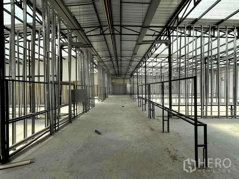 Warehouse for rent in Sai Noi, Nonthaburi - Central aisle through the warehouse with metal framing, high truss ceiling and a roller door ahead.