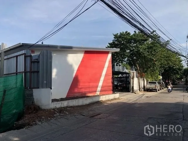 地 出租在Phra Khanong, Bangkok - 街景：红白立面的低层建筑与电线杆。