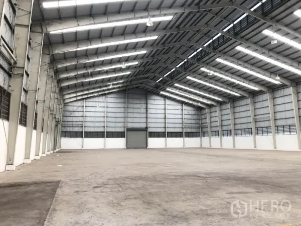 Factory for rent in Wang Noi, Phra Nakhon Si Ayutthaya - Spacious warehouse interior featuring a high steel truss roof with skylights and a smooth concrete floor.