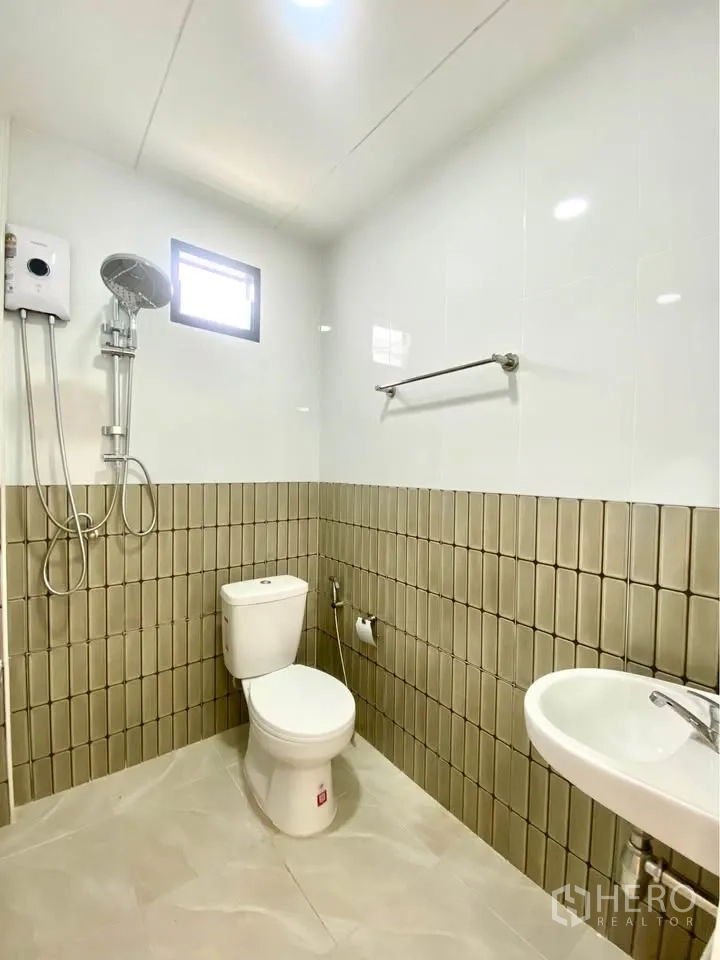 Detached House for rent in Huai Khwang, Bangkok - Tiled bathroom with shower and water heater, toilet, sink and small window.