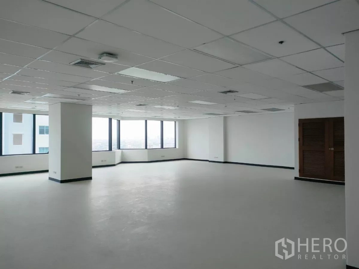 办公空间 出租在Huai Khwang, Bangkok - 宽敞转角办公区，环幕窗景、结构立柱与洁净地面。